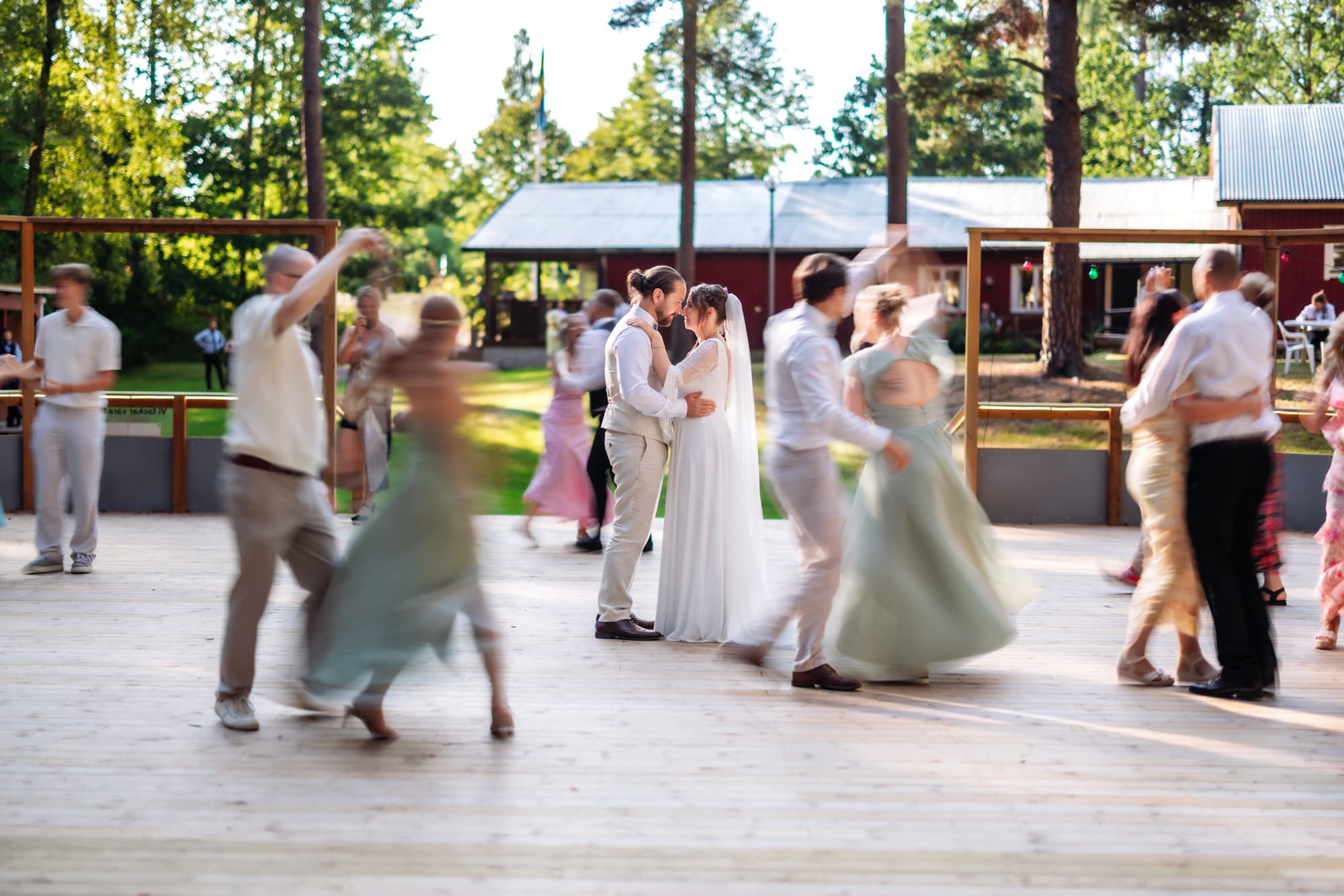Brudparet dansar tätt bland gästerna på en dansbana utomhus, fotograferat av Daniel Eriksson